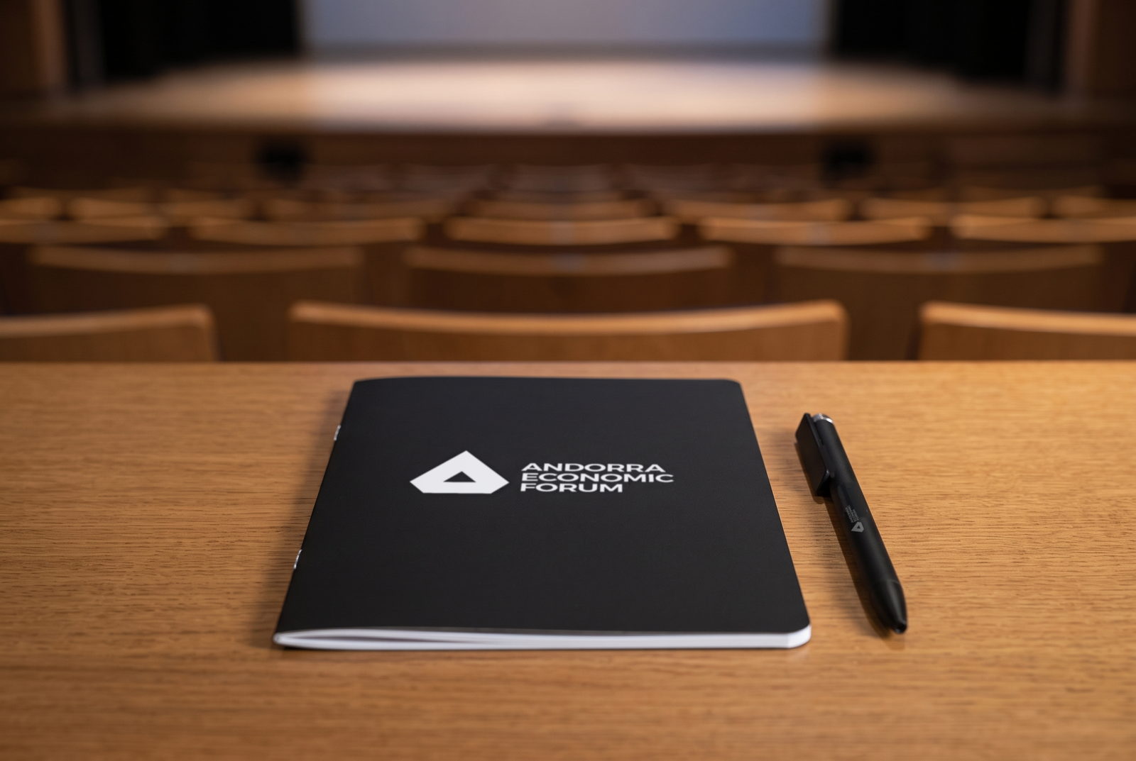 La libreta y el bolígrafo sobre la mesa de un asistente, con la sala de plenos del Centre de Congressos al fondo